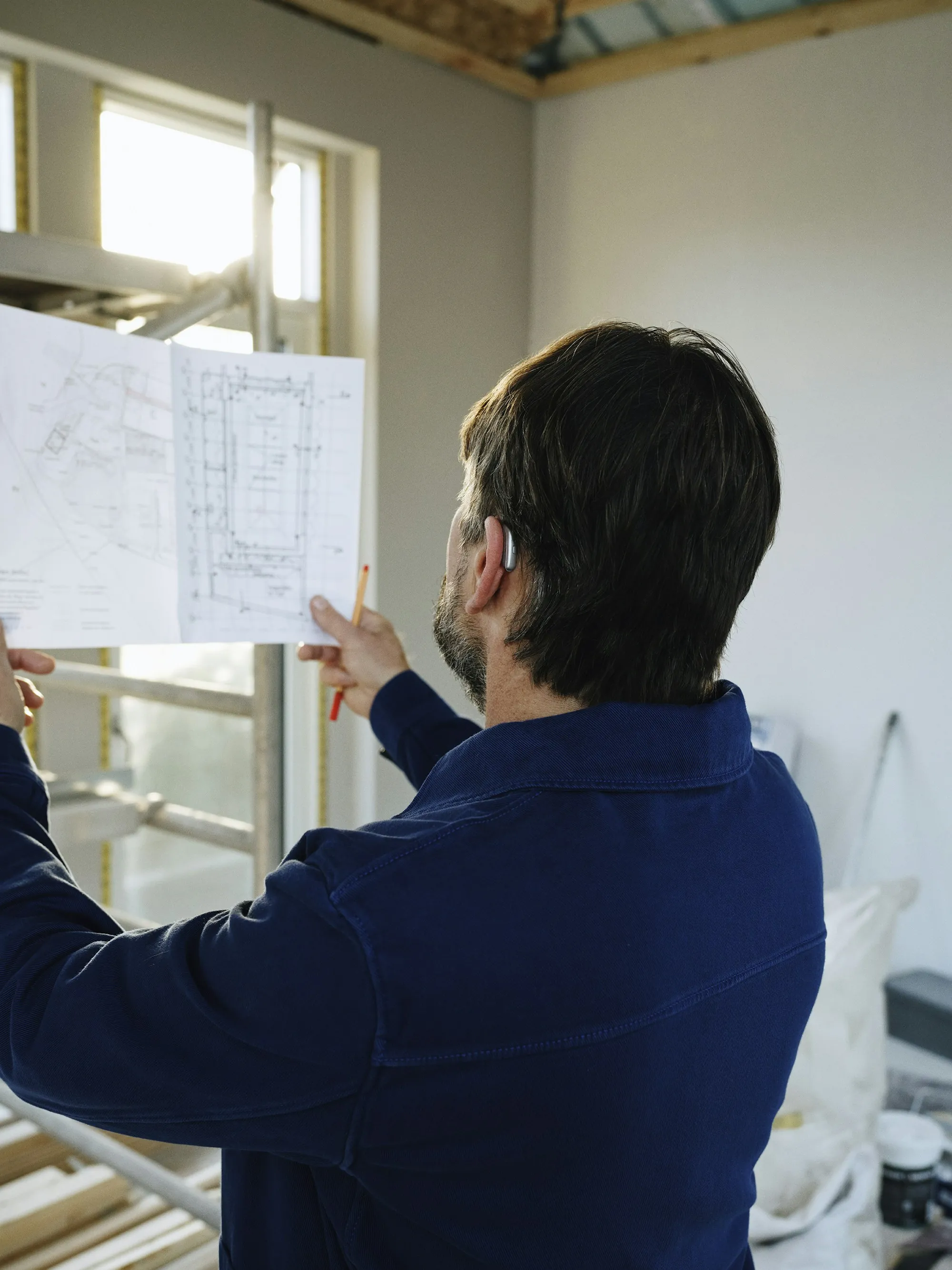 Contractor reviewing plans inside a home under renovation